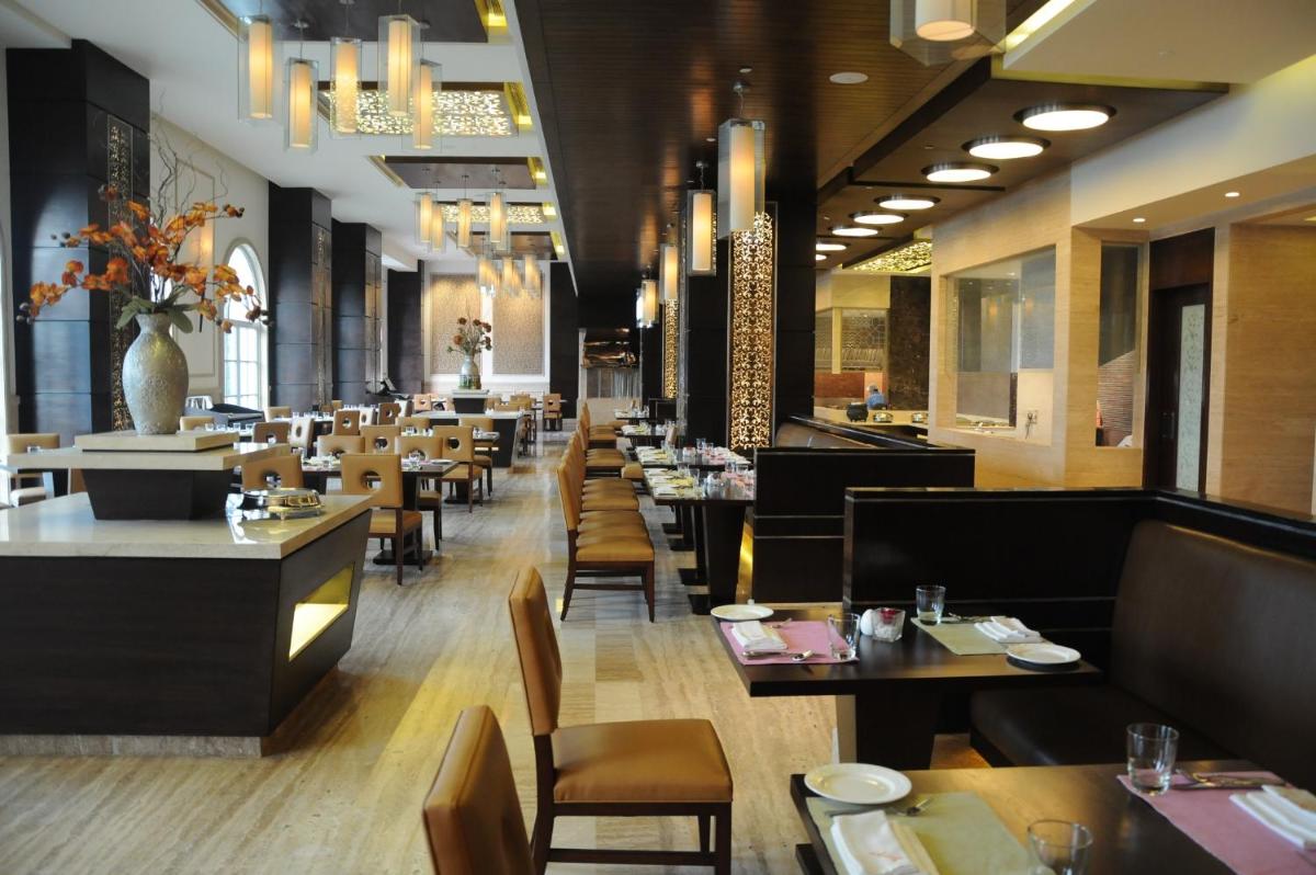 a dining room with tables and chairs and a restaurant at The Pllazio Hotel in Gurgaon