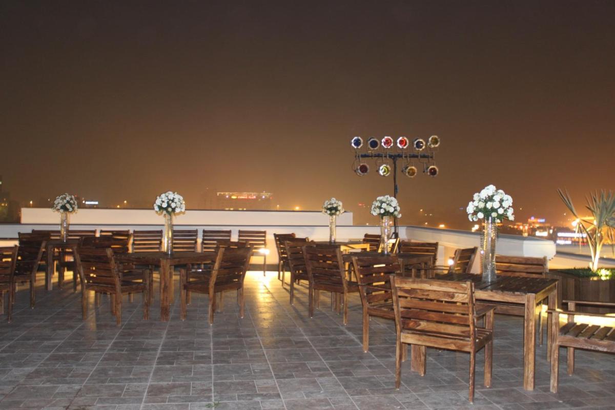 a restaurant with tables and chairs on a rooftop at night at The Pllazio Hotel in Gurgaon