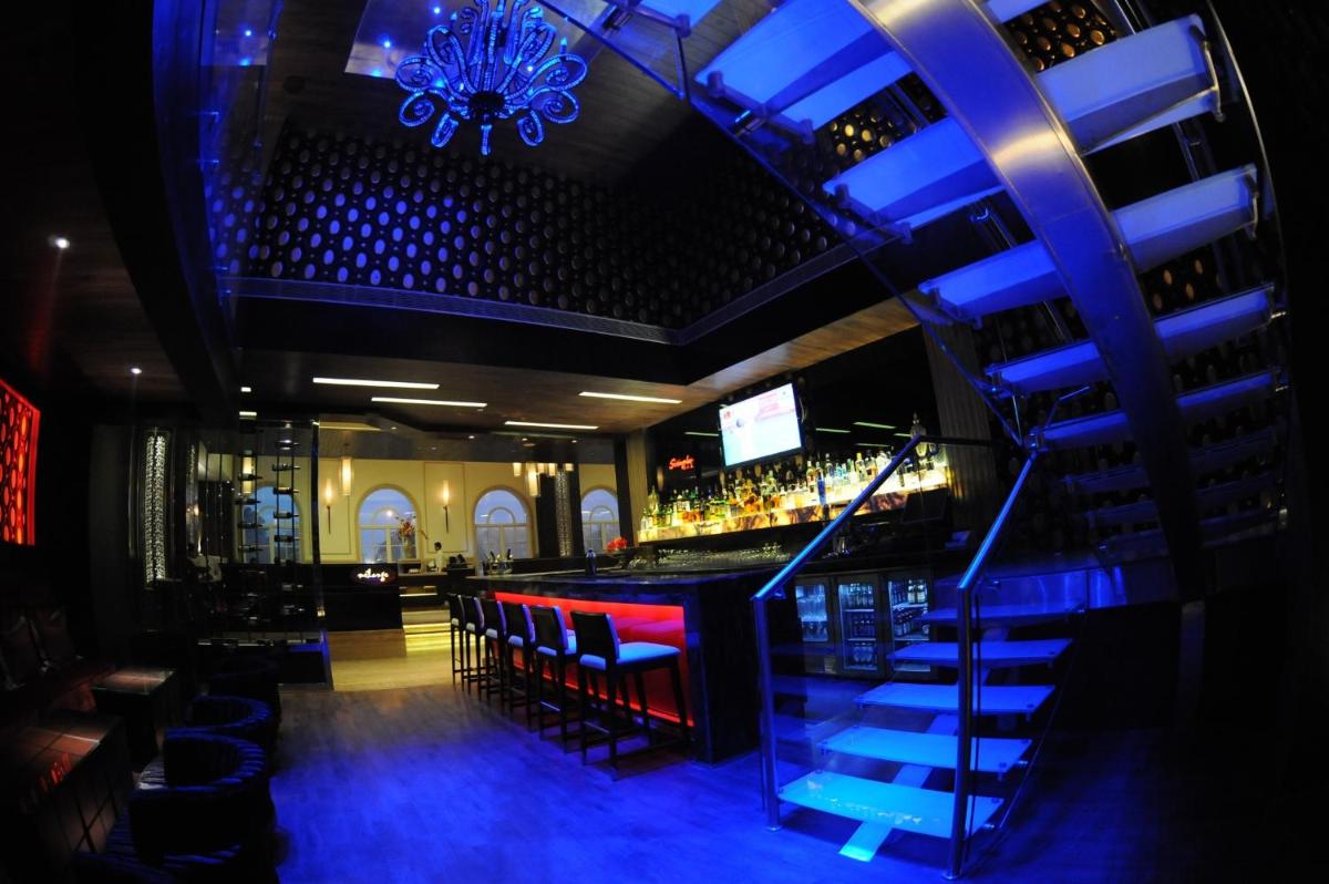 a bar with blue lighting in a bar with stools at The Pllazio Hotel in Gurgaon
