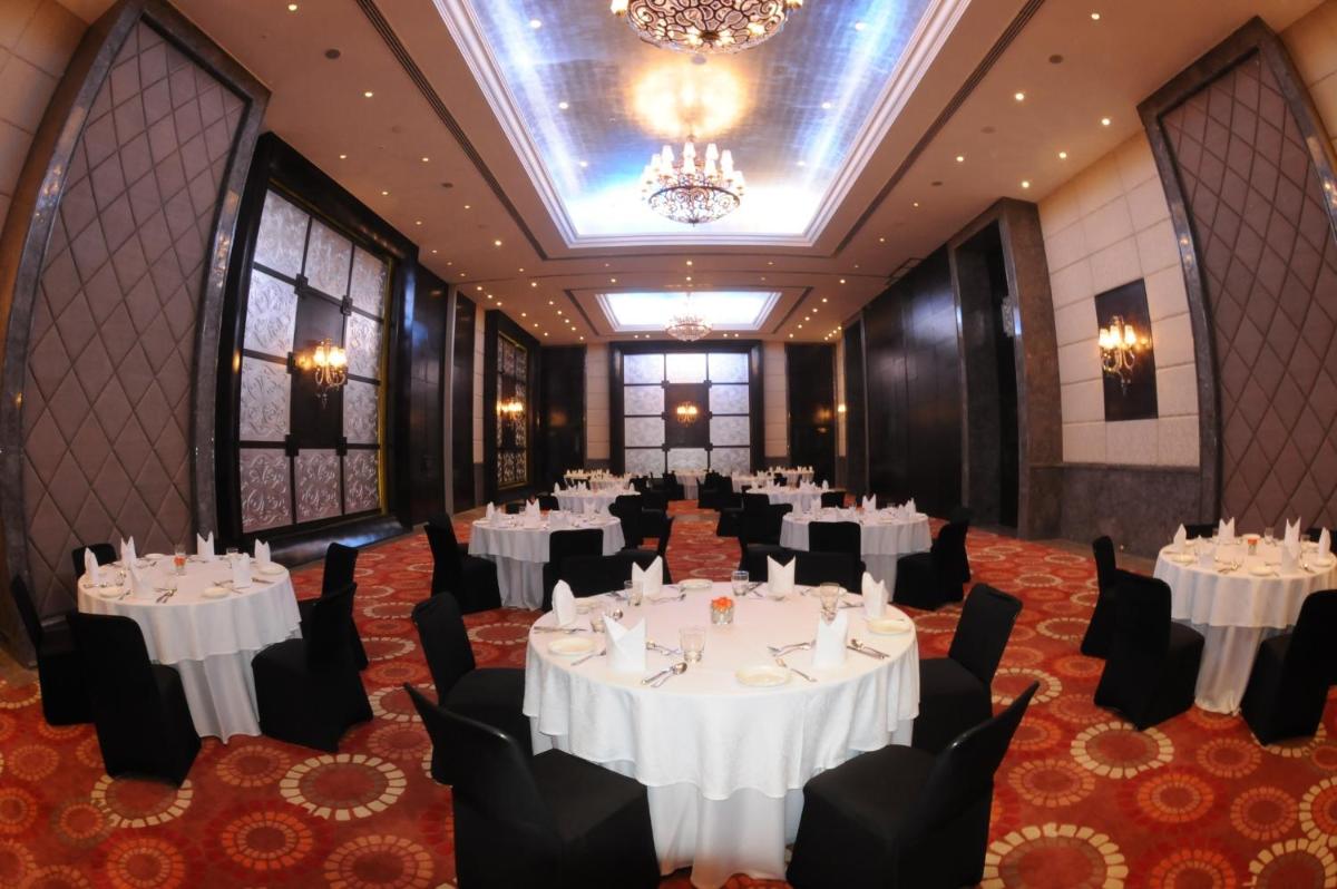 a banquet hall with white tables and chairs and a chandelier at The Pllazio Hotel in Gurgaon