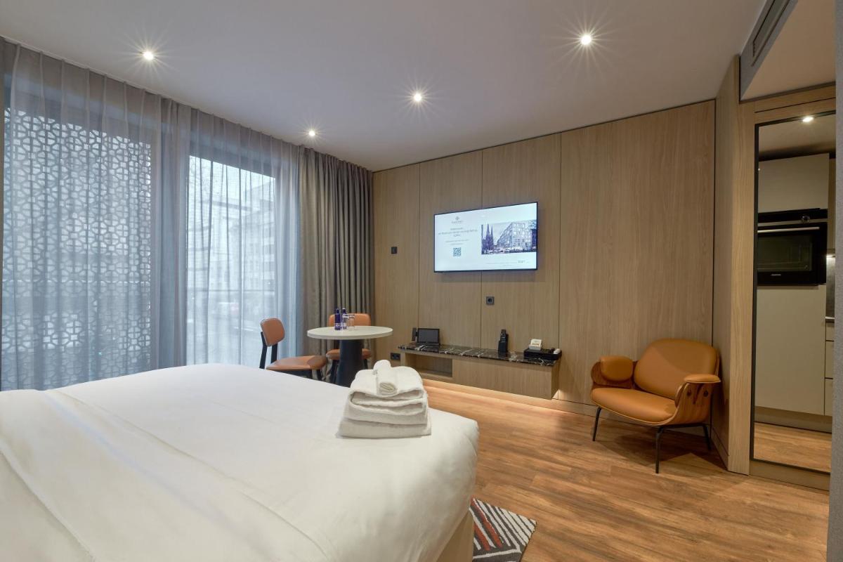 ein Hotelzimmer mit einem Bett und einem Flachbildfernseher in der Unterkunft Fourty Three Luxury Serviced Apartments in Düsseldorf