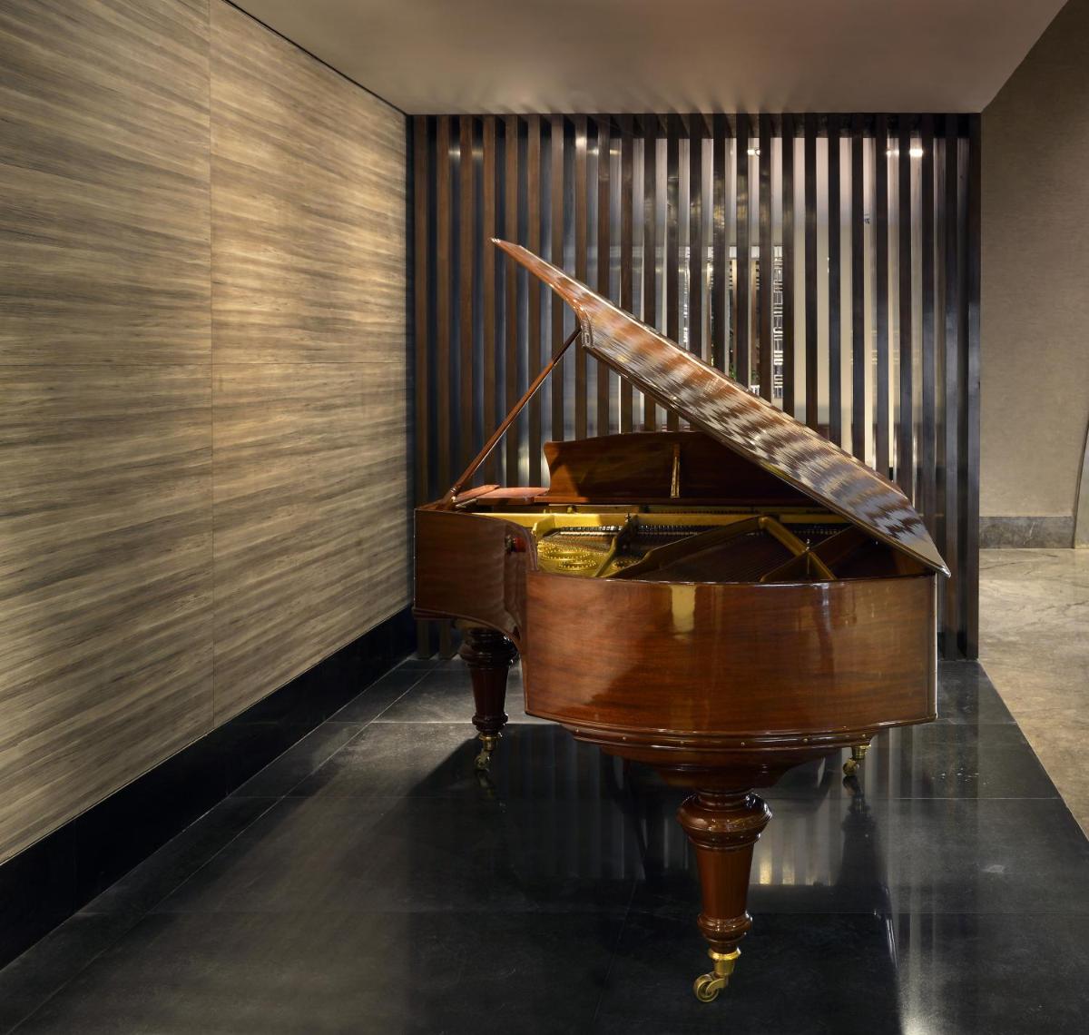 a wooden piano in a room with a wall at The Lalit Great Eastern Kolkata in Kolkata a wooden piano in a room with a wall at The Lalit Great Eastern Kolkata in Kolkata