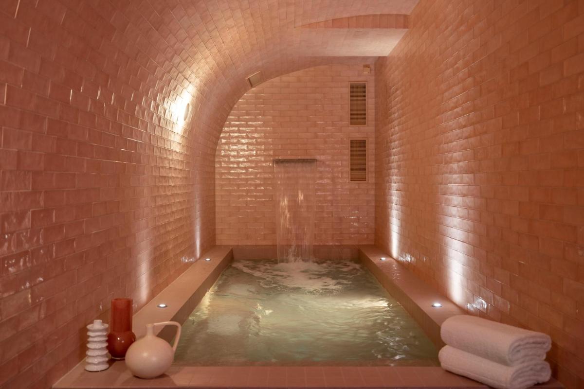 d'une salle de bains avec baignoire dans un mur en briques. dans l'établissement Le Petit Oberkampf Hotel & Spa, à Paris 50 autres photos