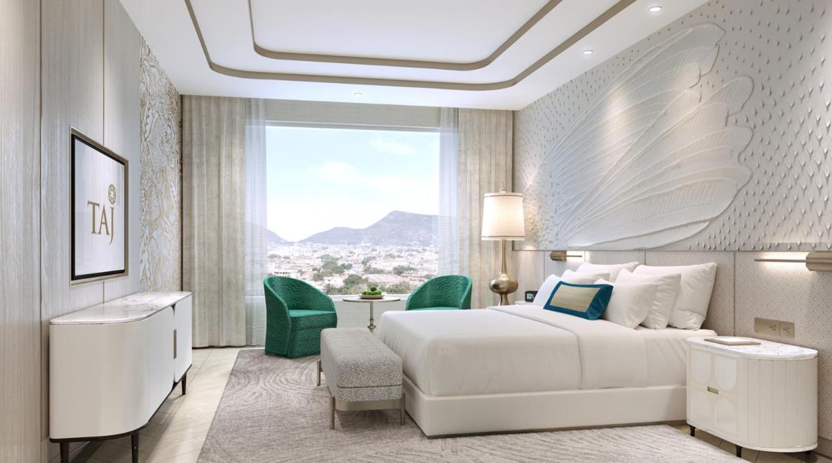 a bedroom with a white bed and a table and chairs at Taj Amer, Jaipur in Jaipur