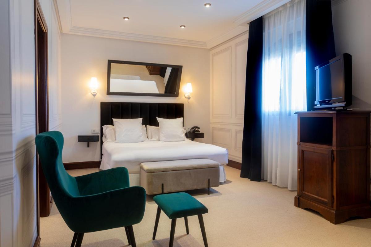 Una habitación de hotel con una cama, una silla y un televisor. en Hotel & Spa Arzuaga, en Quintanilla de Onésimo
