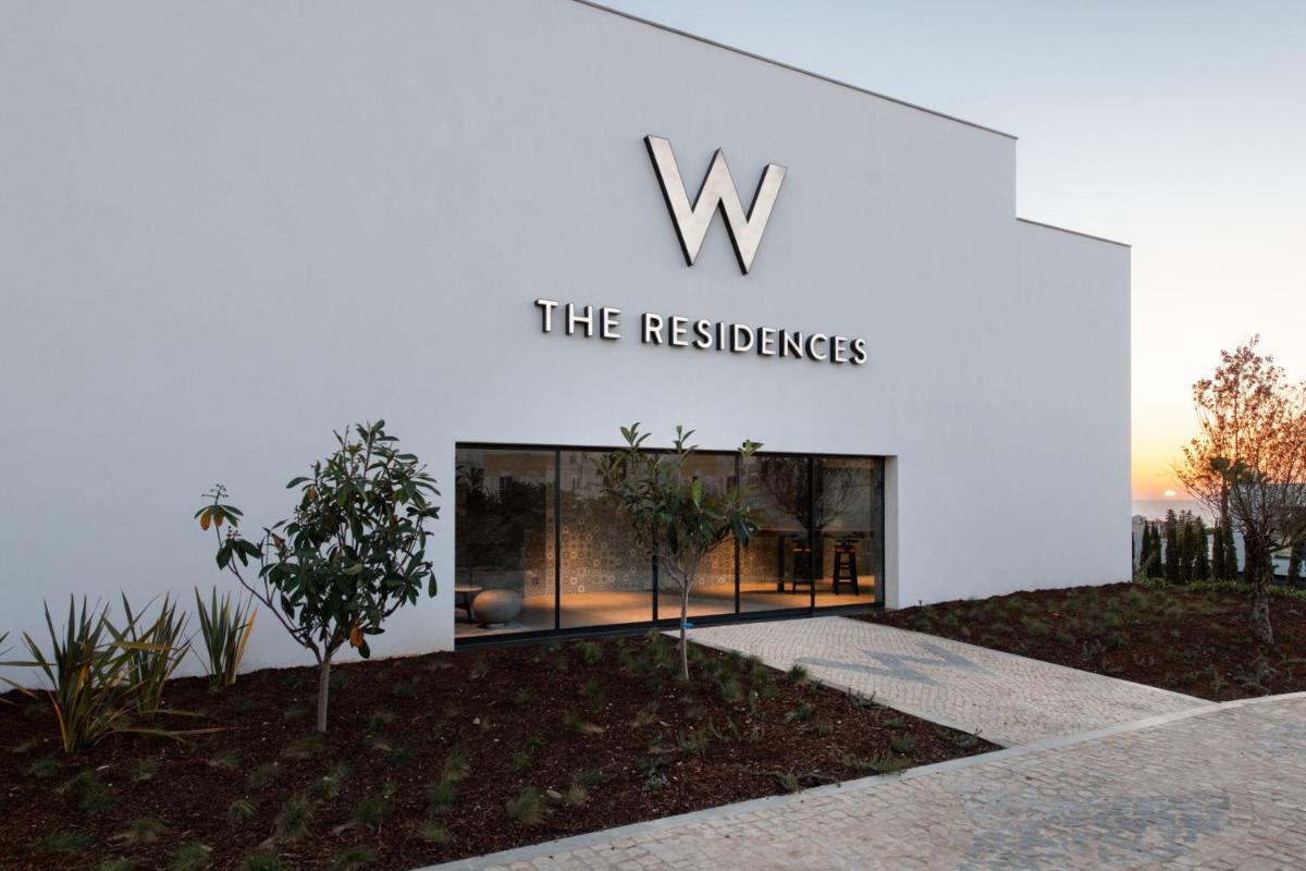 um edifício branco com um cartaz em W Residences Algarve em Albufeira um edifício branco com um cartaz em W Residences Algarve em Albufeira