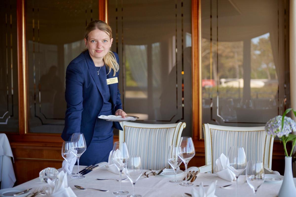 Eine Frau, die einen Teller vor einem Tisch hält. in der Unterkunft Badhotel Sternhagen in Cuxhaven + 37 Fotos
