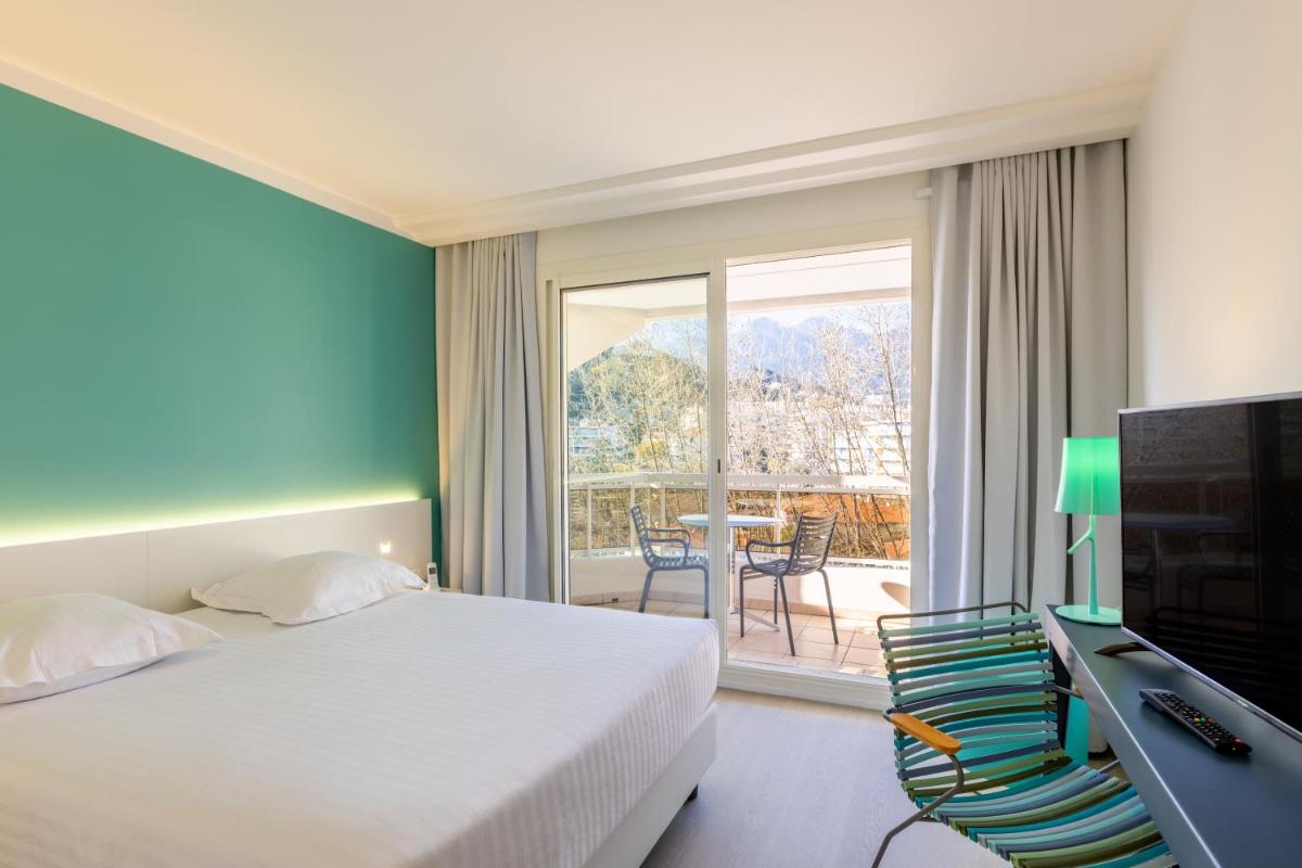 Cette chambre comprend un lit, une télévision et un balcon. dans l'établissement Hôtel Riva Art & Spa, à Menton