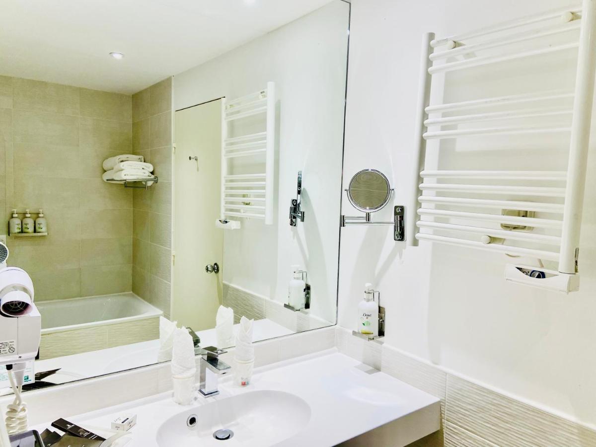 une salle de bain blanche avec un lavabo et un miroir dans l'établissement Holiday Inn Calais Coquelles by IHG, à Coquelles 81 autres photos