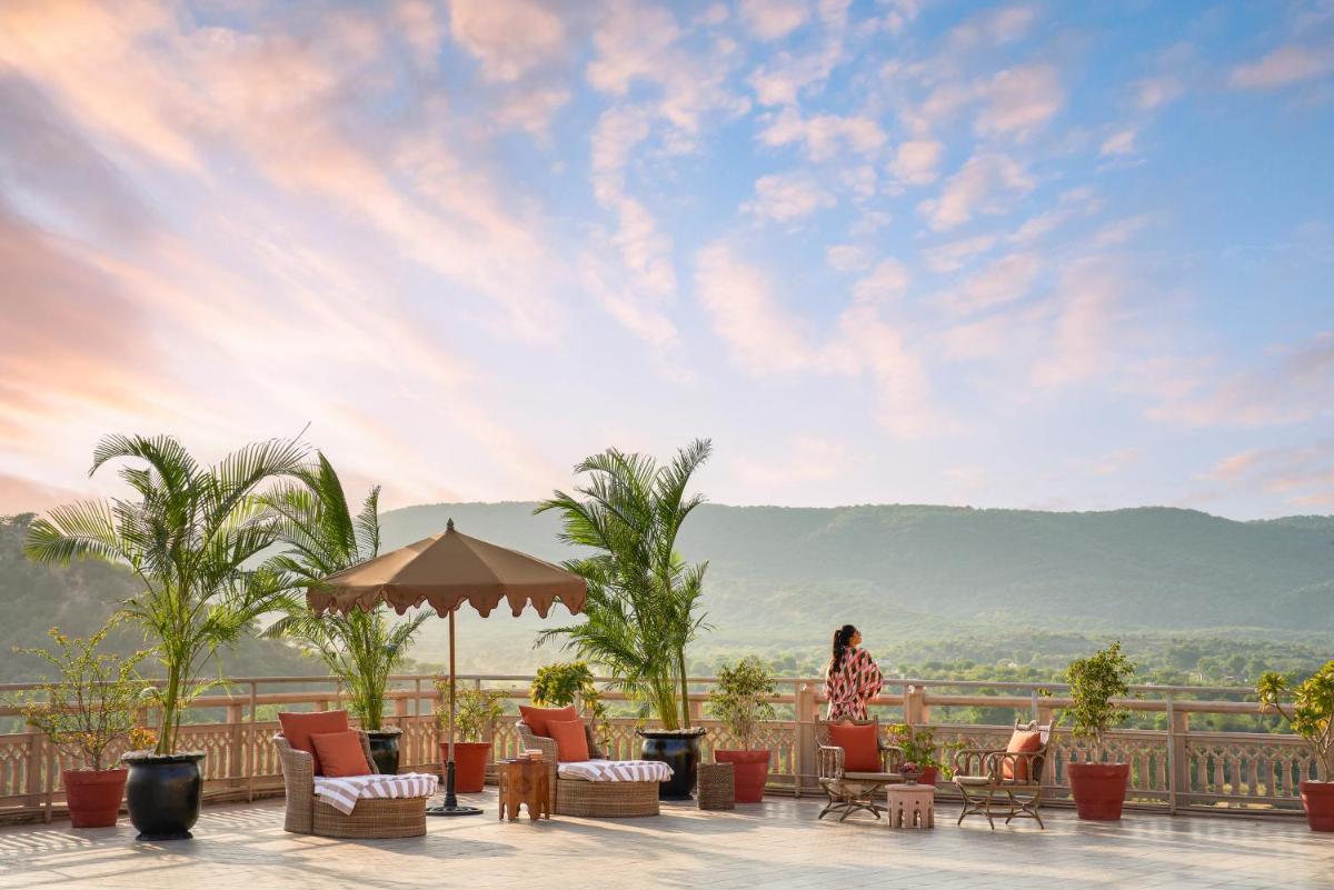 a woman sitting on a patio with a view of the mountains at Fairmont Jaipur in Jaipur
