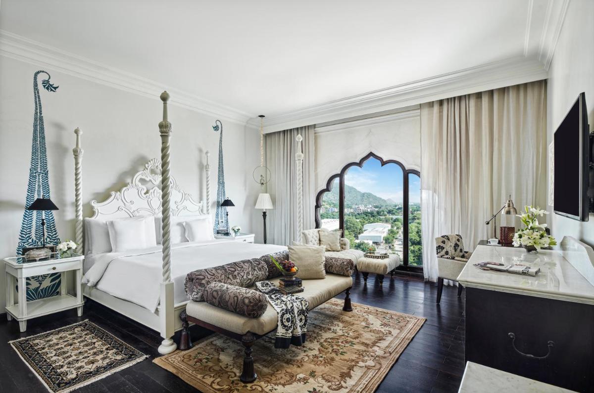 a bedroom with a white bed and a living room at Fairmont Jaipur in Jaipur