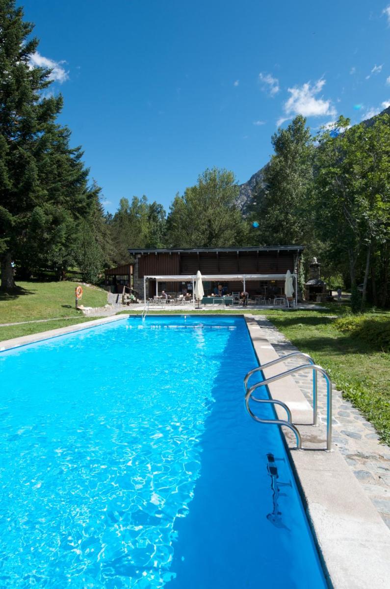 una piscina azul con un edificio de fondo en Hotel Caldas, en Caldes de Boí