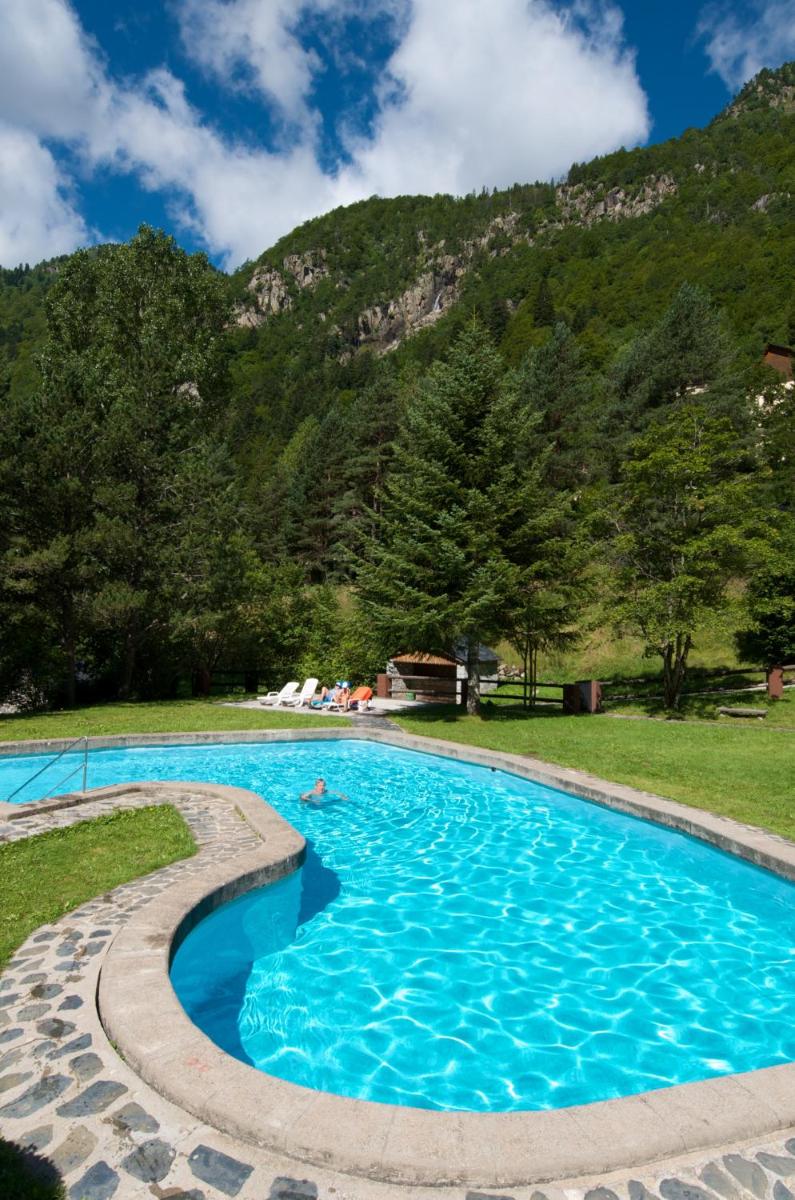 una piscina con montañas al fondo en Hotel Caldas, en Caldes de Boí