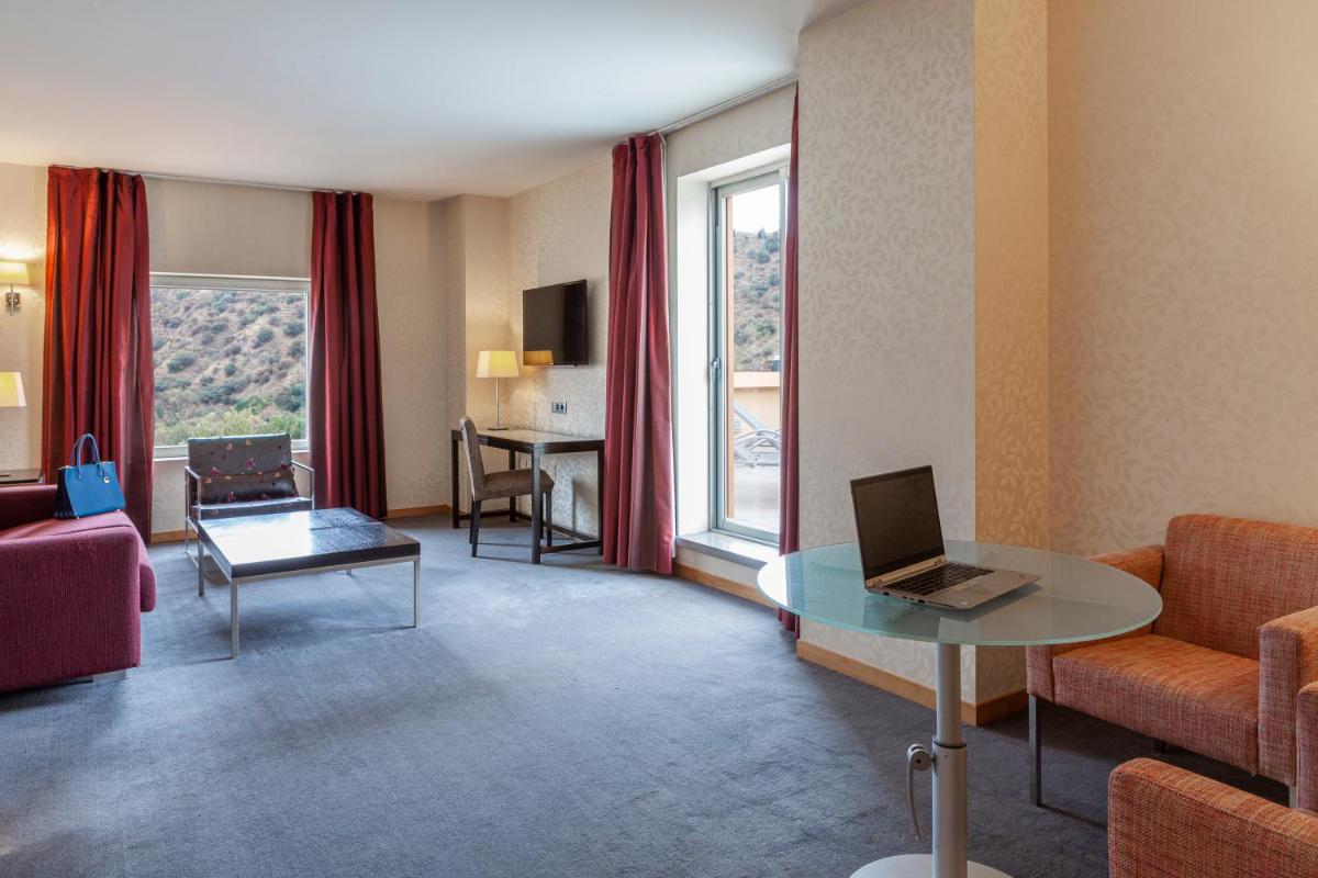 una sala de estar con un ordenador portátil sobre una mesa de cristal en Hotel Macià Real De La Alhambra, en Granada