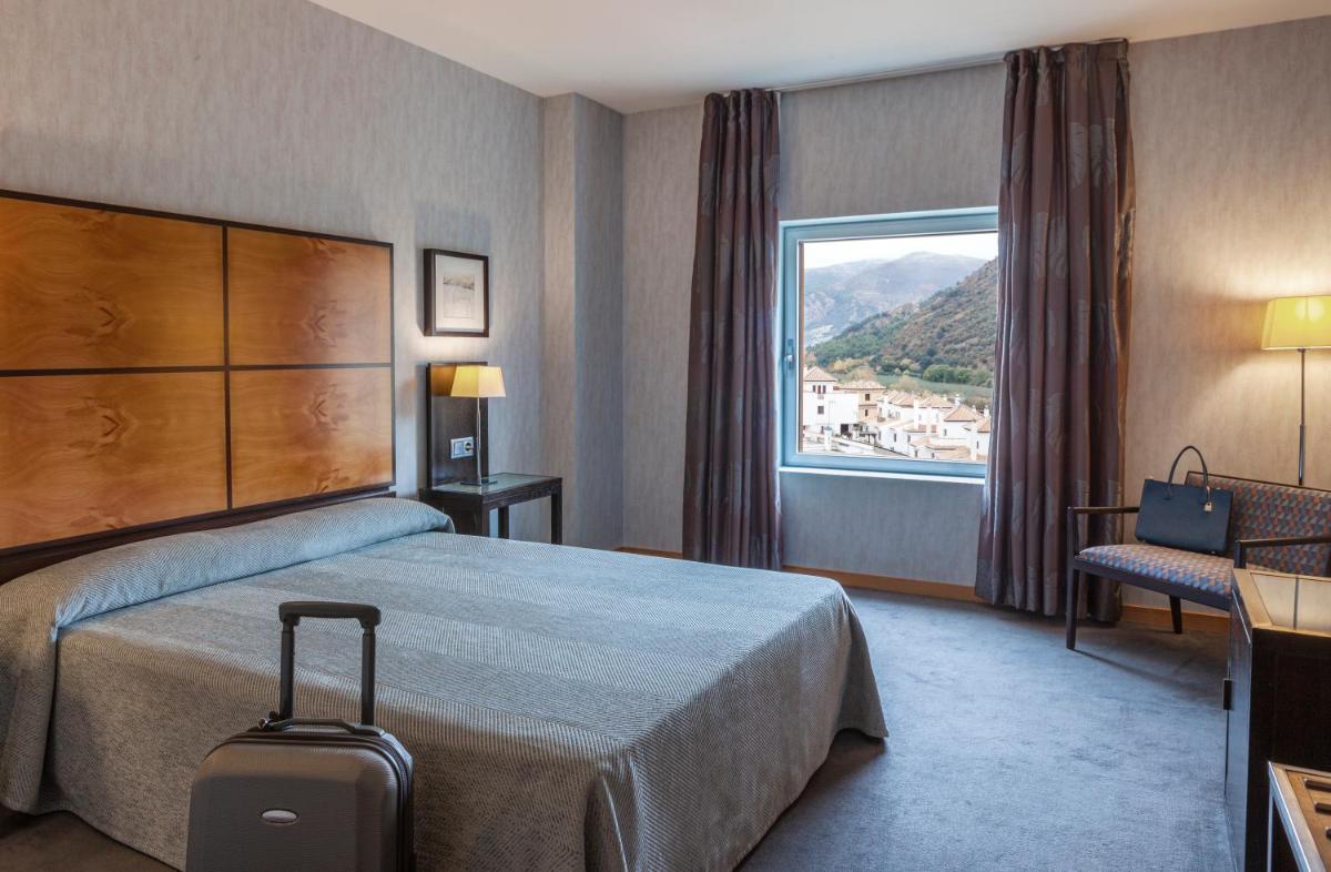 Una habitación de hotel con una cama y una ventana. en Hotel Macià Real De La Alhambra, en Granada