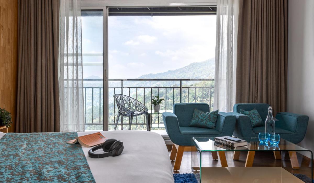 a hotel room with a bed and a large window at The Panoramic Getaway in Munnar