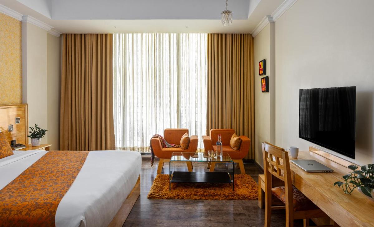 a hotel room with a bed and a television at The Panoramic Getaway in Munnar