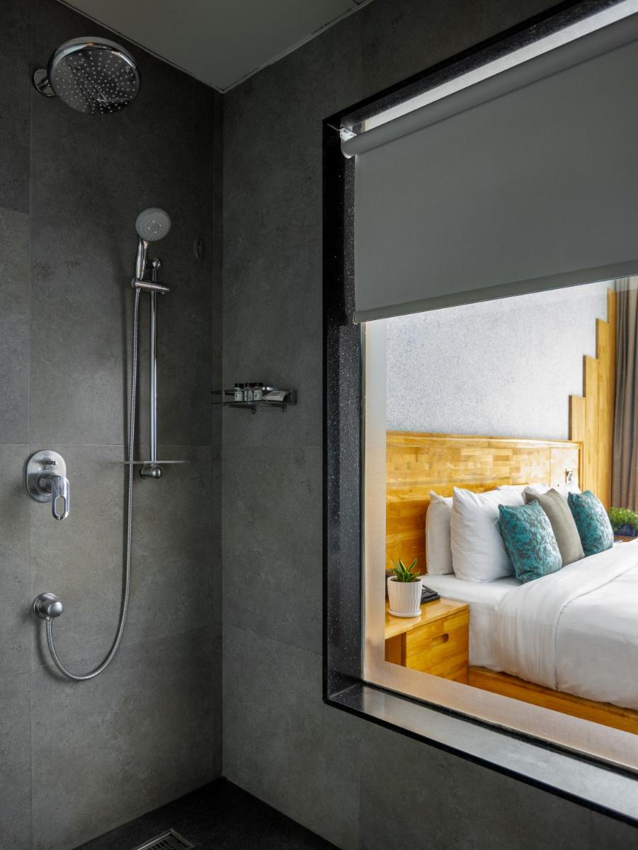 a bathroom with a shower and a bed with a window at The Panoramic Getaway in Munnar