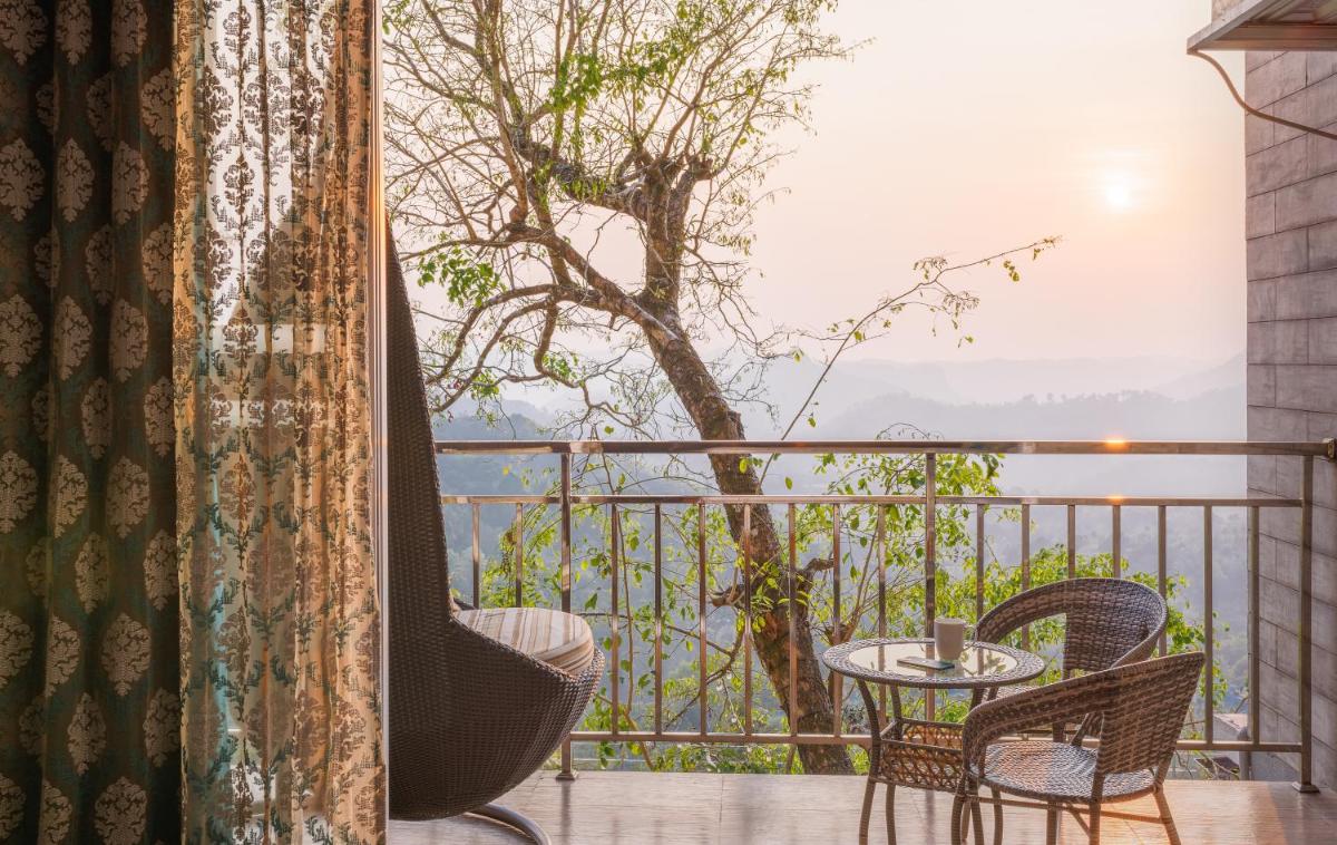 a balcony with chairs and a table and a tree at The Panoramic Getaway in Munnar