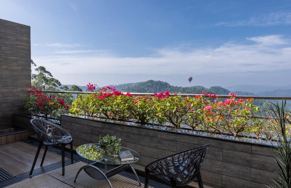 a balcony with two chairs and a table and flowers at The Panoramic Getaway in Munnar
