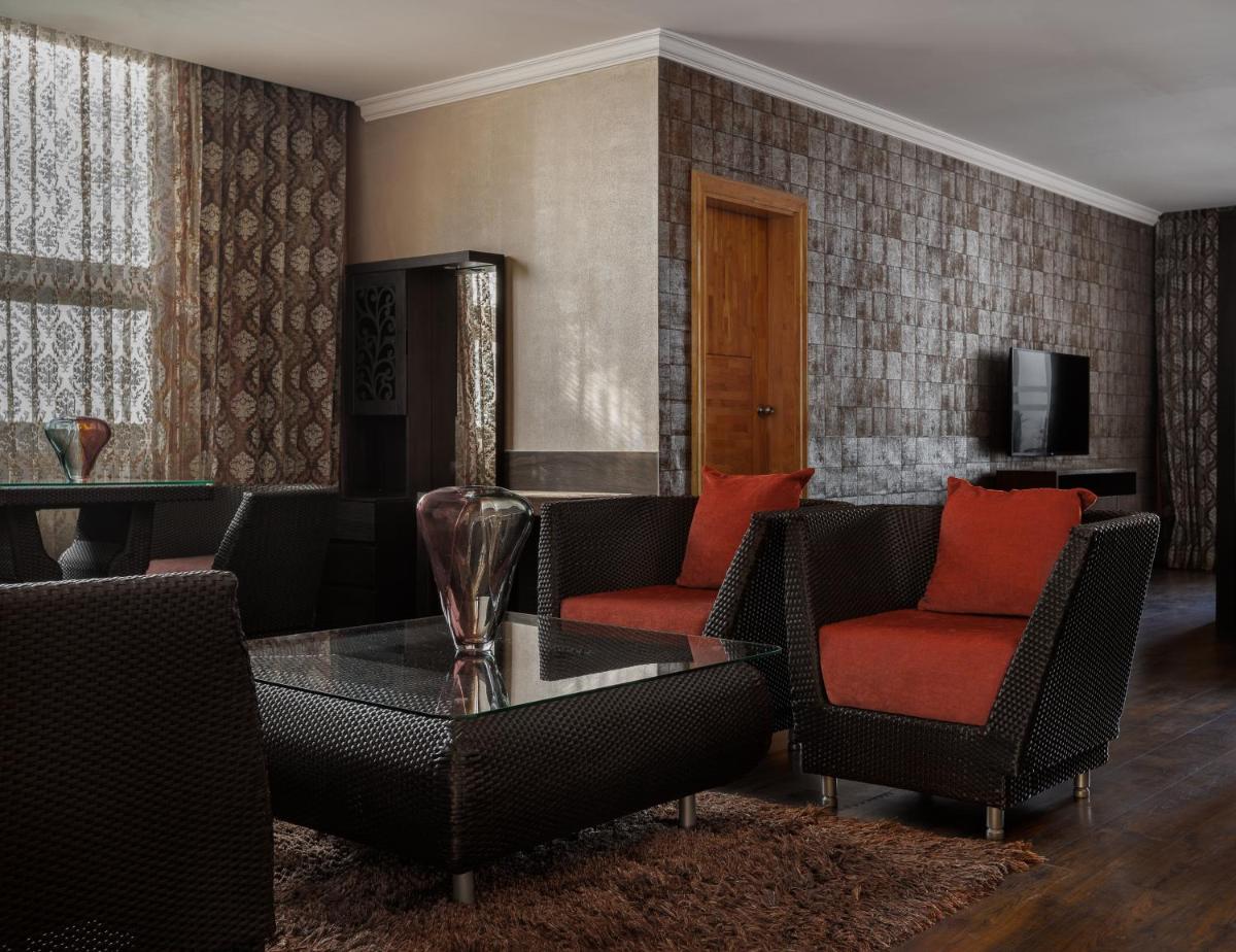 a living room with chairs and a table and a television at The Panoramic Getaway in Munnar