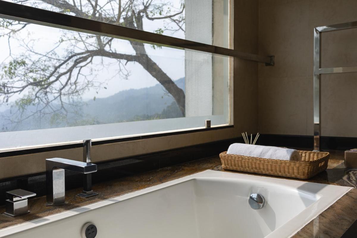 a bath tub in a bathroom with a large window at The Panoramic Getaway in Munnar