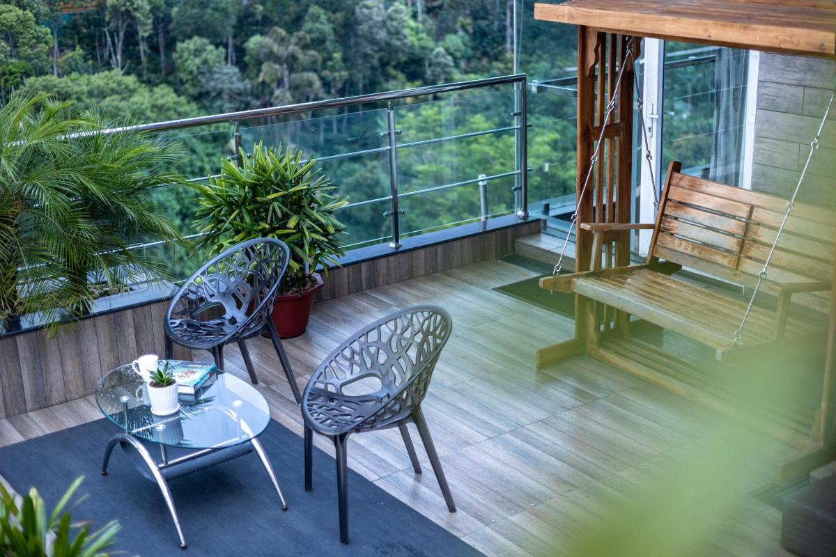 a balcony with two chairs and a table and a bench at The Panoramic Getaway in Munnar
