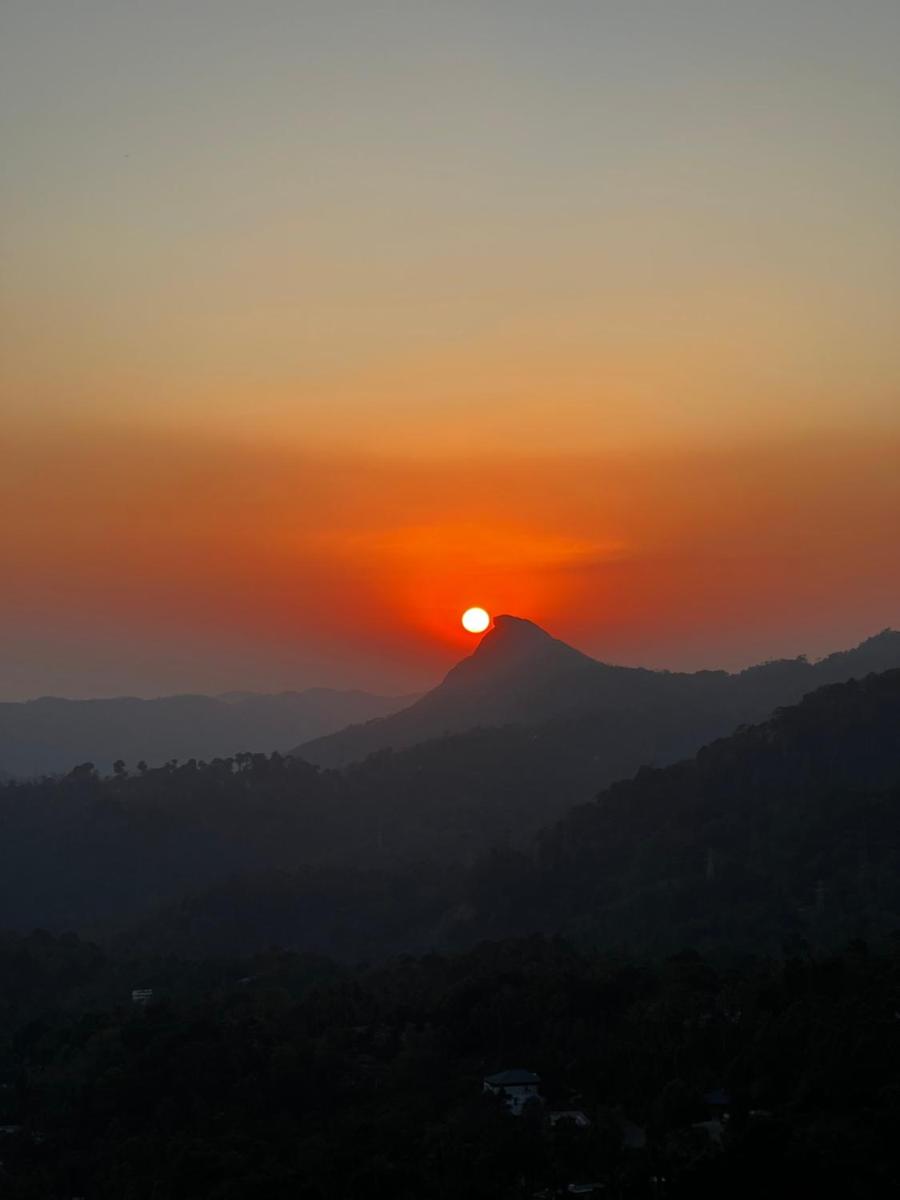 a sunset over a mountain with the sun setting at The Panoramic Getaway in Munnar