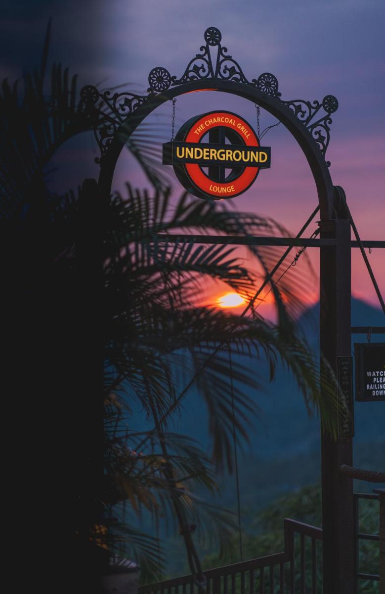 an arch with a sign with the sunset in the background at The Panoramic Getaway in Munnar