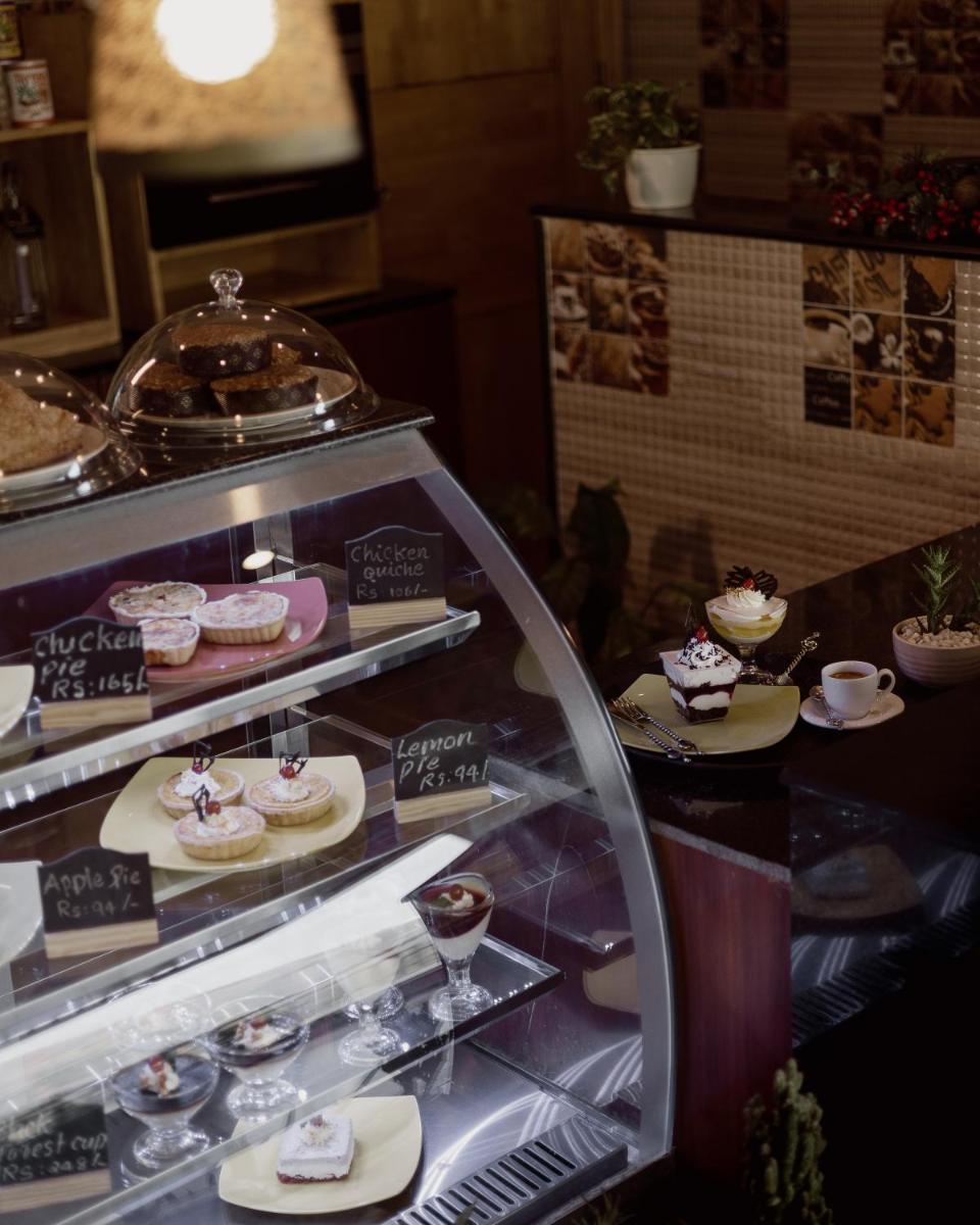 a display case filled with lots of cakes and desserts at The Panoramic Getaway in Munnar