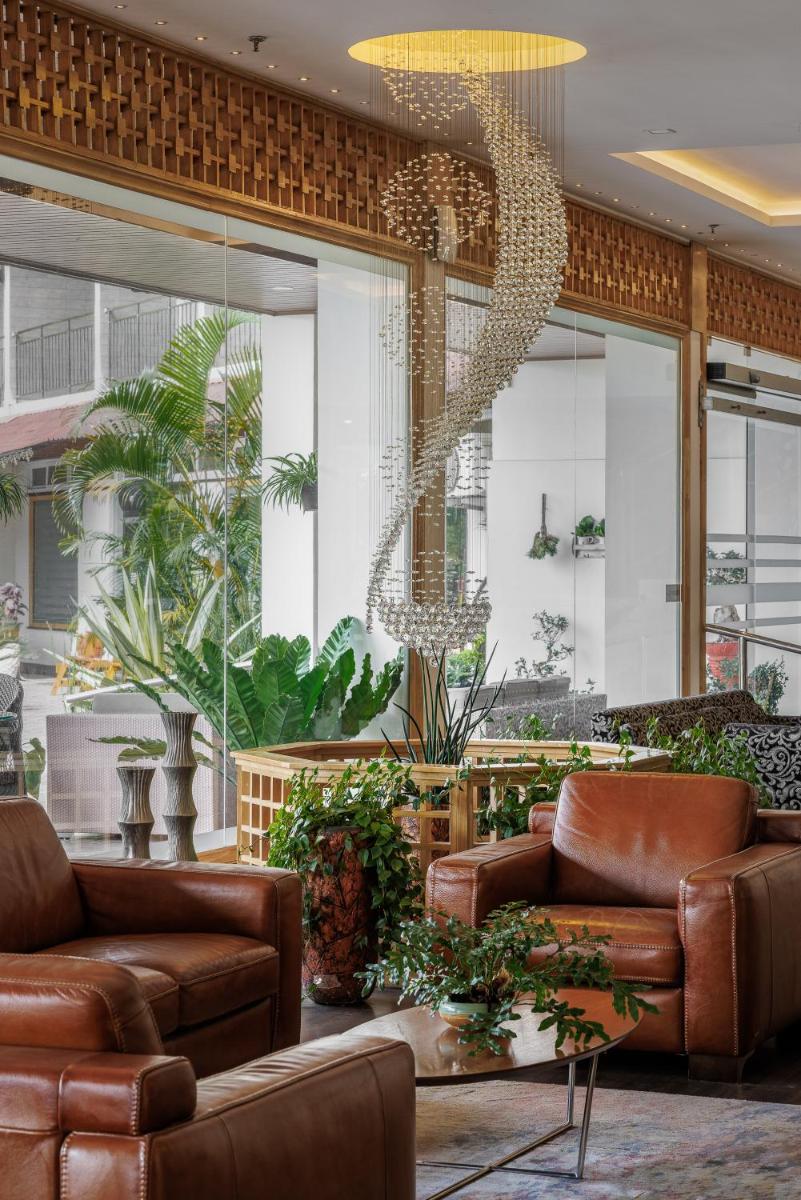 a lobby with brown leather couches and plants at The Panoramic Getaway in Munnar