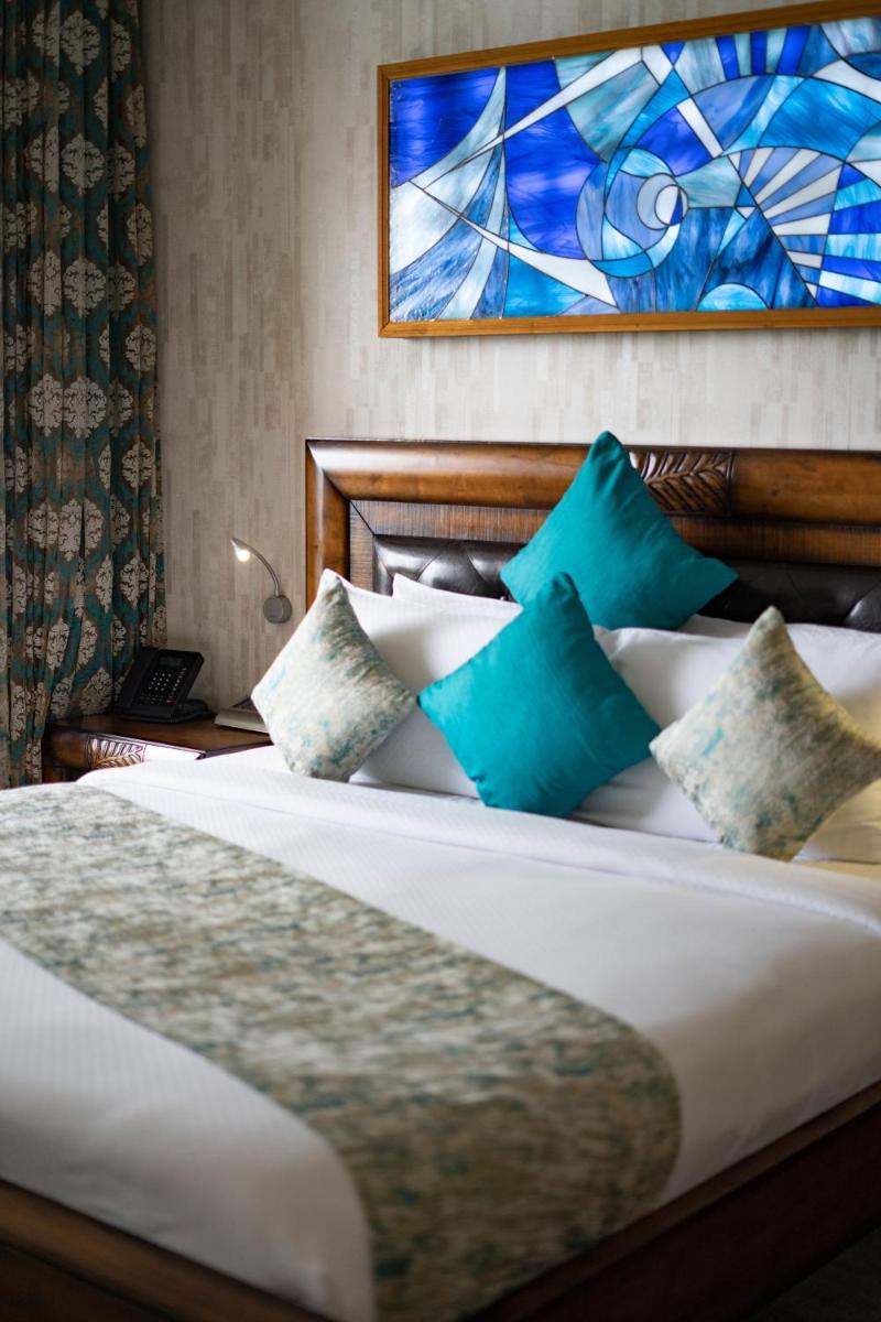 a bedroom with a bed with blue and white pillows at The Panoramic Getaway in Munnar