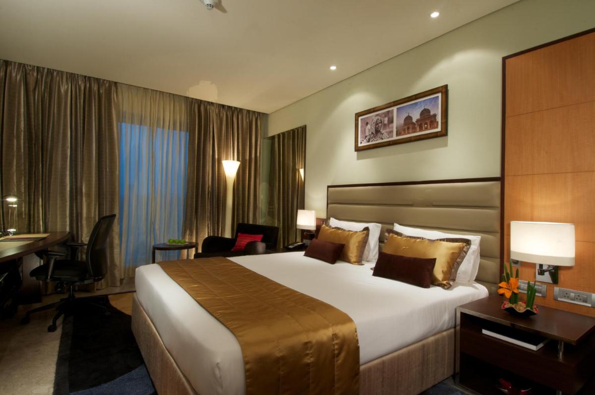 a hotel room with a large bed and a desk at Vivanta Hyderabad, Begumpet in Hyderabad a hotel room with a large bed and a desk at Vivanta Hyderabad, Begumpet in Hyderabad