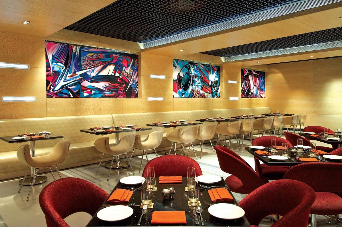 a restaurant with tables and chairs and paintings on the walls at Vivanta Hyderabad, Begumpet in Hyderabad a restaurant with tables and chairs and paintings on the walls at Vivanta Hyderabad, Begumpet in Hyderabad