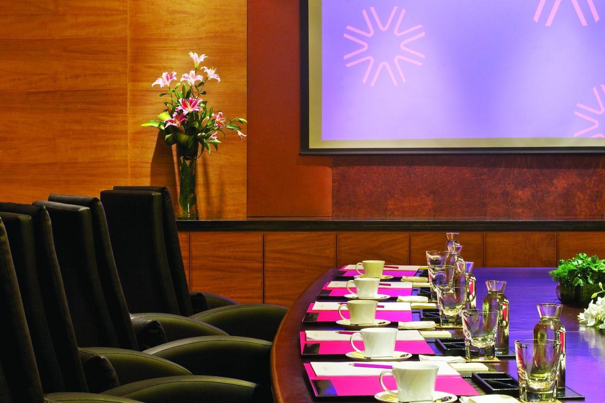 a conference room with a long table with chairs and a screen at Vivanta Hyderabad, Begumpet in Hyderabad a conference room with a long table with chairs and a screen at Vivanta Hyderabad, Begumpet in Hyderabad