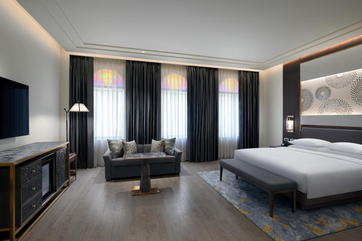 a bedroom with a king sized bed and a couch at Hyatt Regency Jaipur Mansarovar in Jaipur a bedroom with a king sized bed and a couch at Hyatt Regency Jaipur Mansarovar in Jaipur