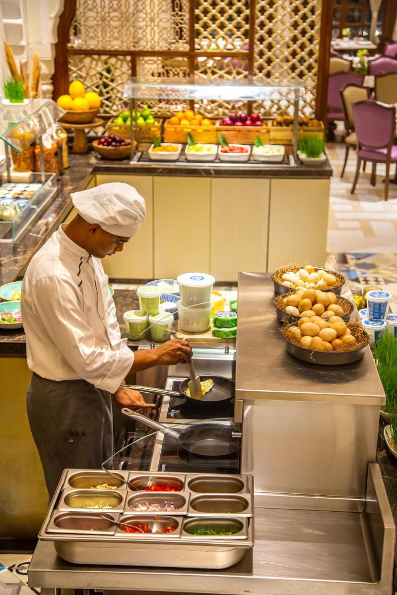 a chef preparing food in a restaurant kitchen at Hyatt Regency Jaipur Mansarovar in Jaipur a chef preparing food in a restaurant kitchen at Hyatt Regency Jaipur Mansarovar in Jaipur