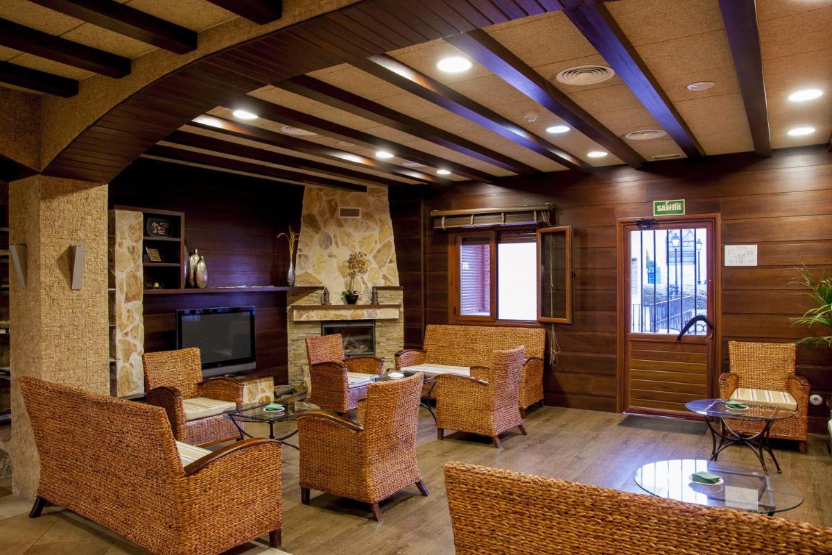 un vestíbulo con sillas y mesas de mimbre y TV en Hotel Comendador, en Carranque