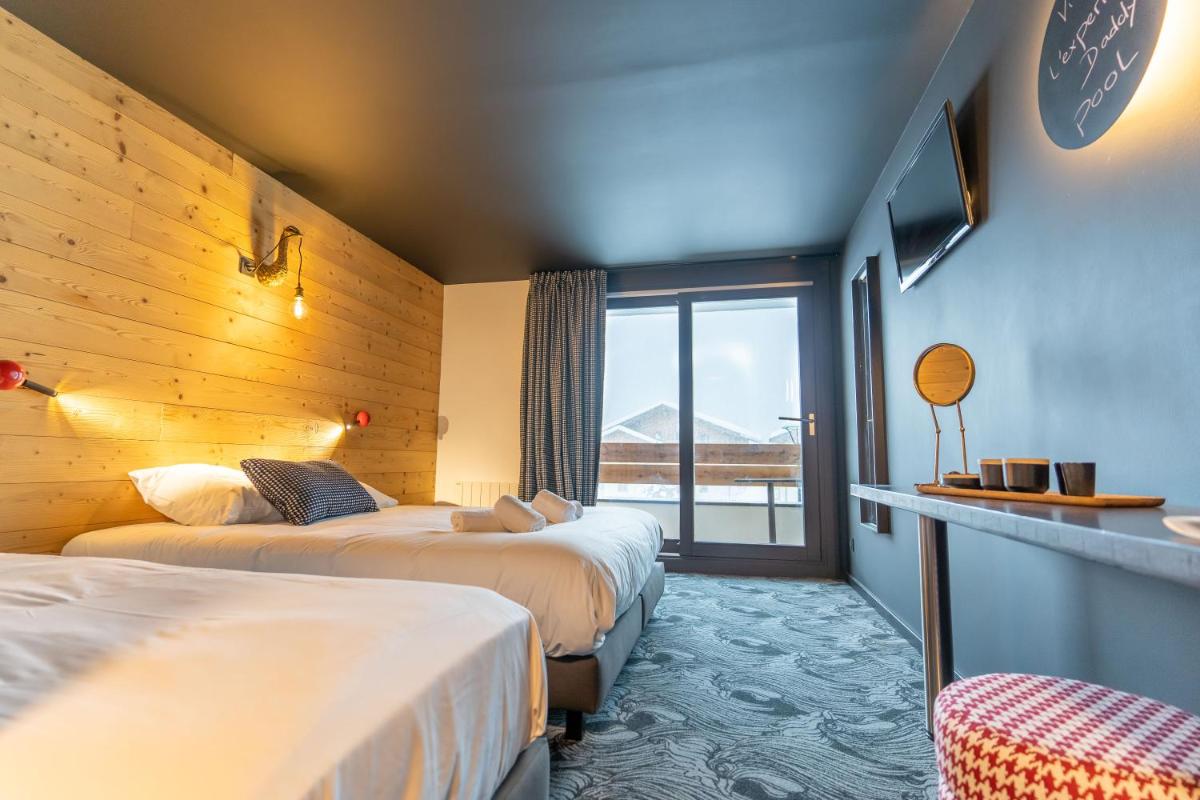 une chambre d'hôtel avec deux lits et une fenêtre dans l'établissement Hôtel Le Cristal Lodge - TERRESENS, à Saint-Chaffrey