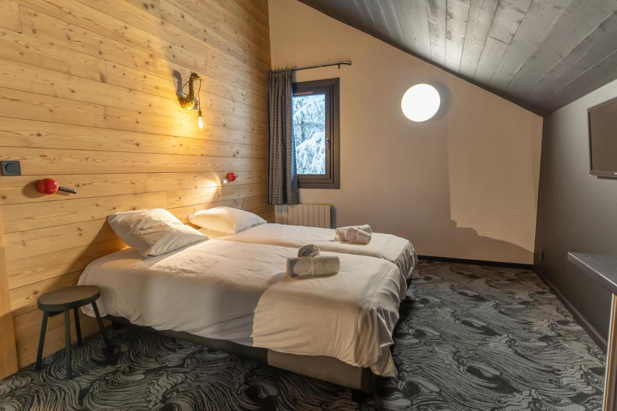 - une chambre avec un grand lit dans un mur en bois dans l'établissement Hôtel Le Cristal Lodge - TERRESENS, à Saint-Chaffrey
