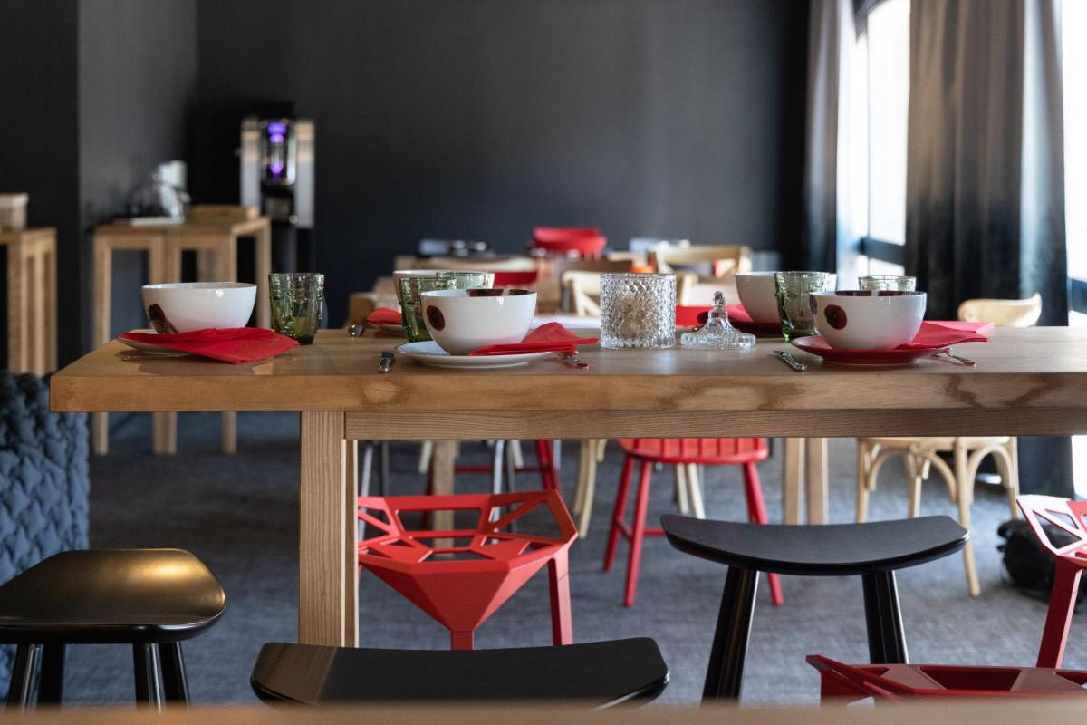 - une table en bois avec des chaises rouges et une table avec des tasses dans l'établissement Hôtel Le Cristal Lodge - TERRESENS, à Saint-Chaffrey 25 autres photos