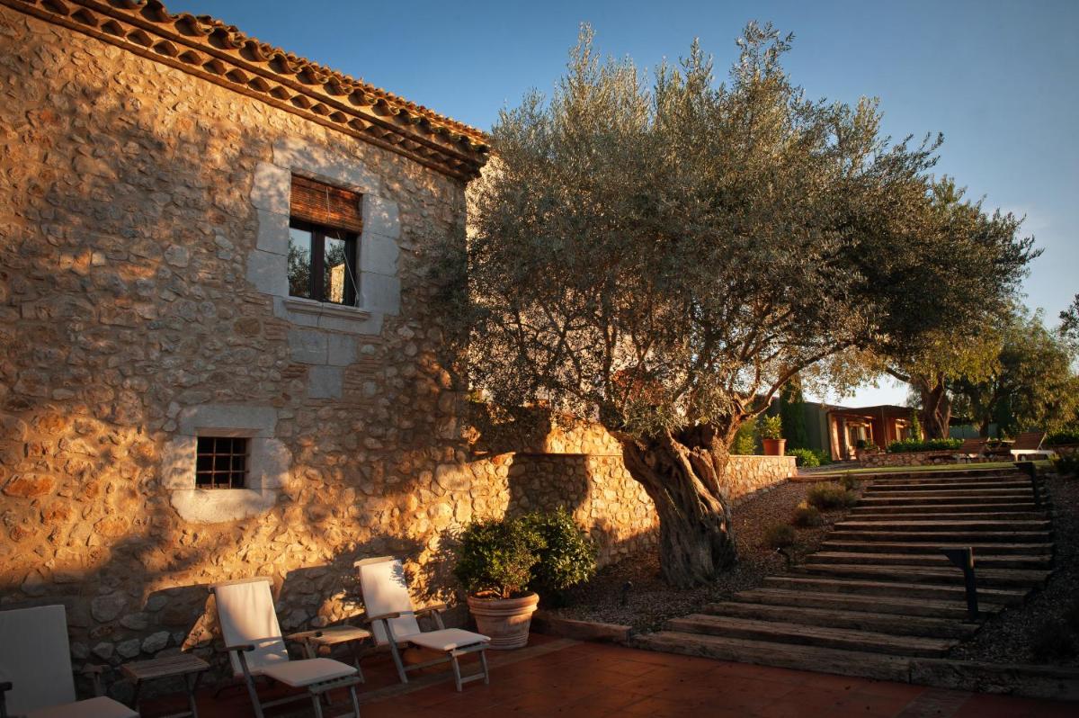 un edificio de piedra con sillas, un árbol y escaleras en Mas Falgarona Hotel Boutique & SPA, en Avinyonet de Puigventós