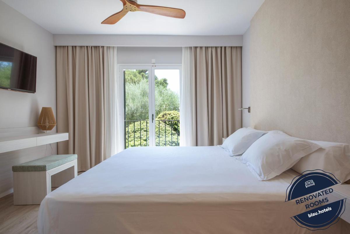 Un dormitorio con una cama grande con ventilador de techo. en Blau Colònia Sant Jordi, en Colonia de Sant Jordi