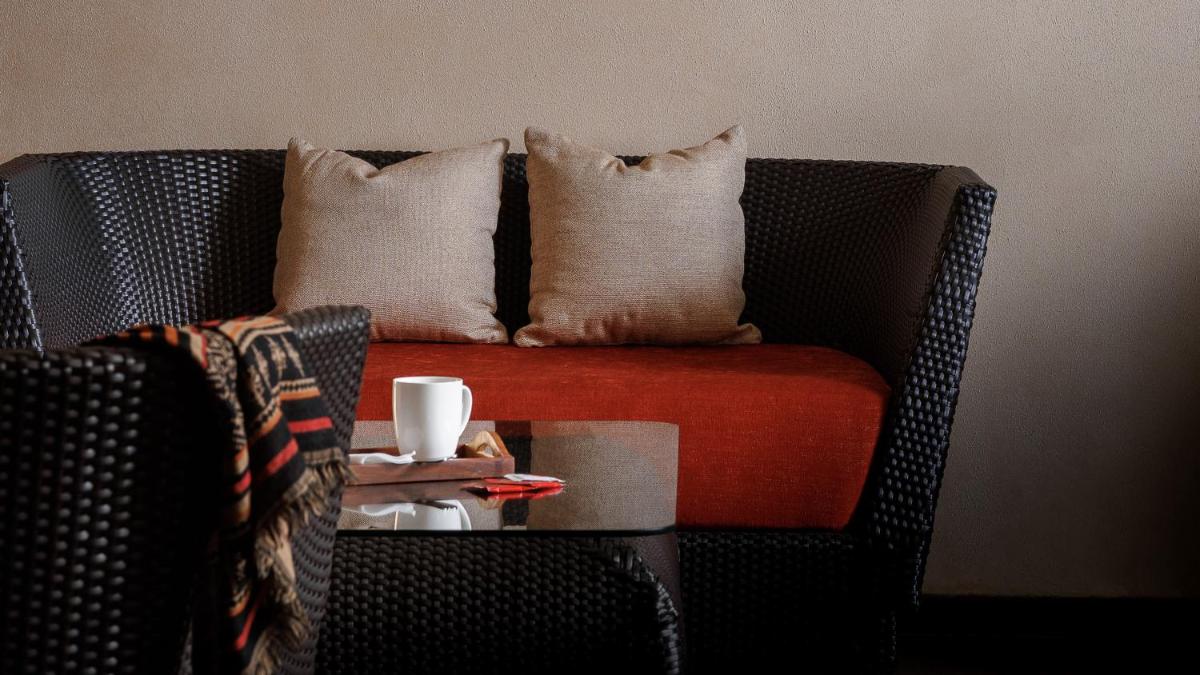 a couch with pillows and a cup on a table at The Panoramic Getaway in Munnar