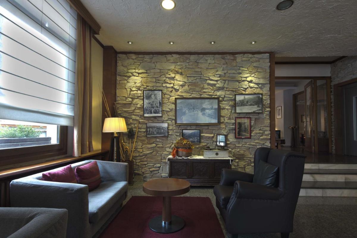 sala de estar con 2 sillas y pared de piedra en Hotel Restaurant Pessets & SPA, en Sort