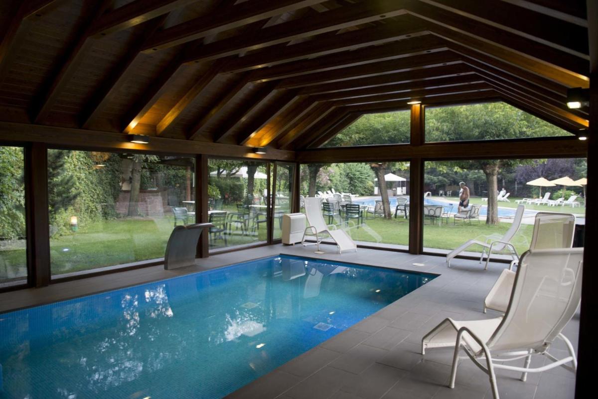 una piscina en una casa con sillas alrededor en Hotel Restaurant Pessets & SPA, en Sort