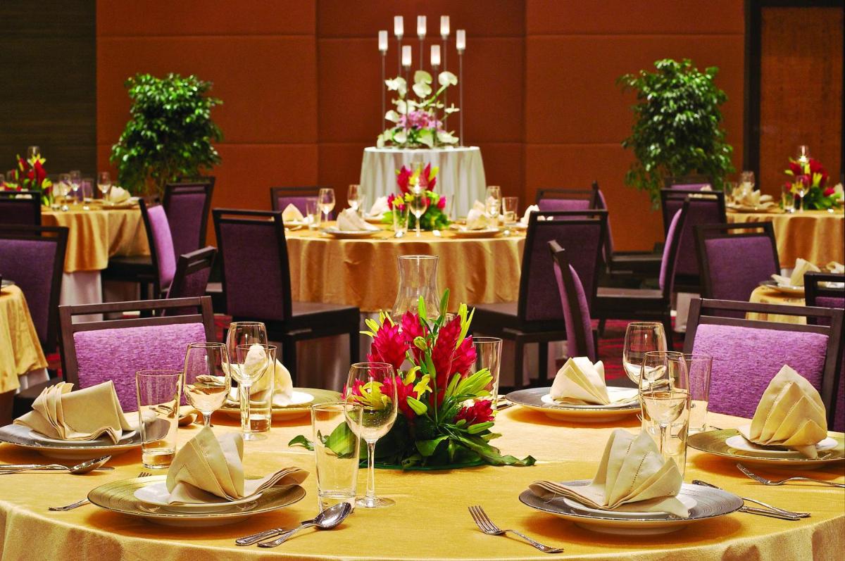 a dining room with tables and chairs with glasses and flowers at Vivanta Hyderabad, Begumpet in Hyderabad a dining room with tables and chairs with glasses and flowers at Vivanta Hyderabad, Begumpet in Hyderabad