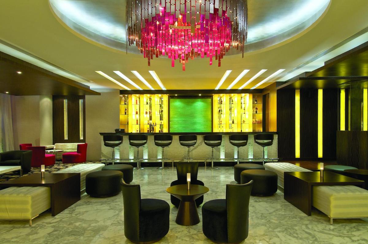 a lobby with a bar with chairs and a chandelier at Vivanta Hyderabad, Begumpet in Hyderabad a lobby with a bar with chairs and a chandelier at Vivanta Hyderabad, Begumpet in Hyderabad