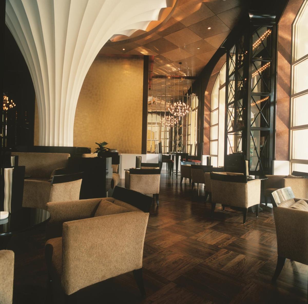 a dining room with chairs and tables and windows at Trident Gurgaon in Gurgaon