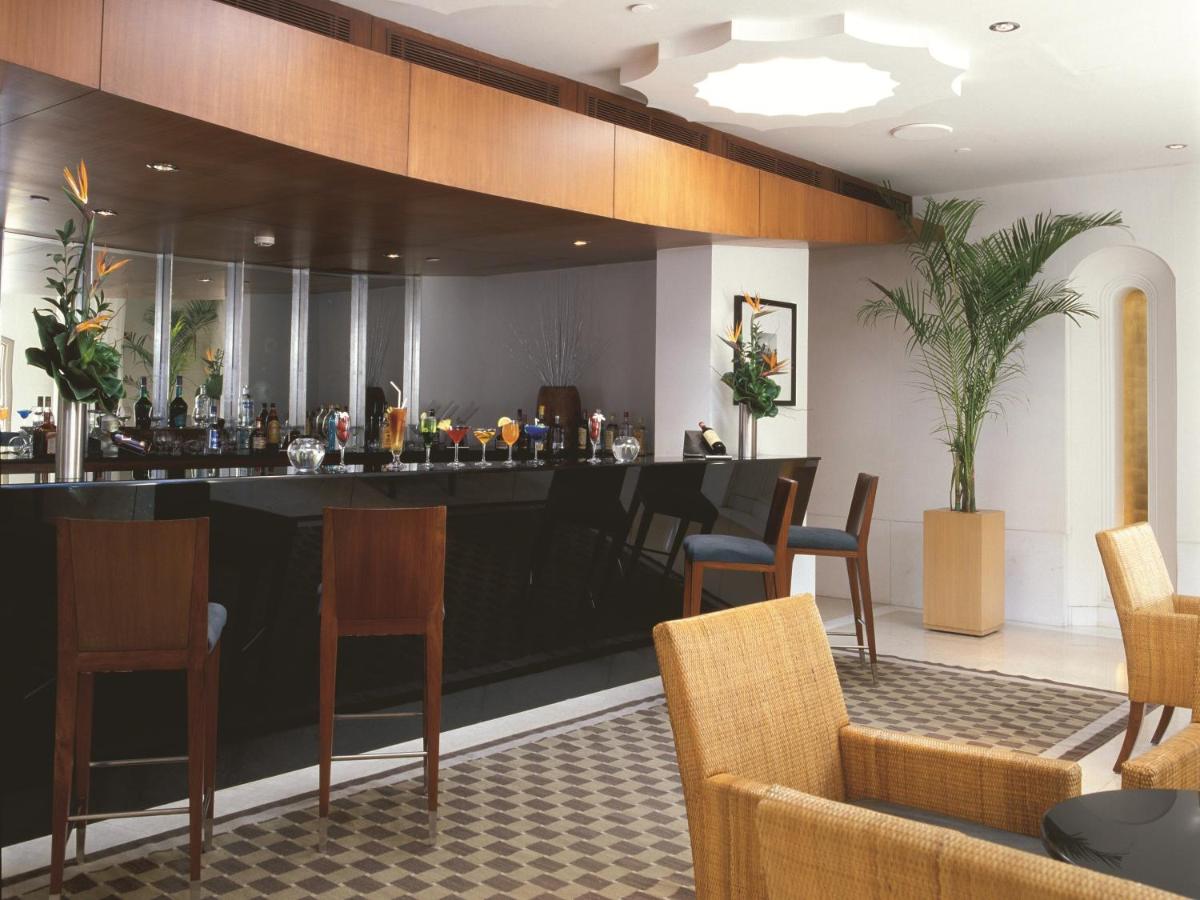 a bar in a hotel lobby with chairs and tables at Trident Gurgaon in Gurgaon